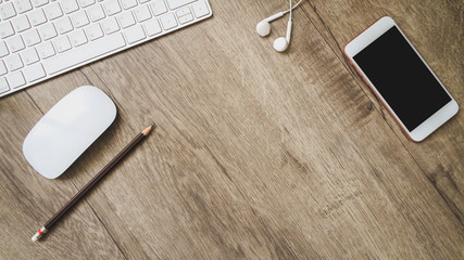 Modern wood office desk table with keyboard computer and smartphone with black screen over and pencil, headphones on wooden desk Top view with copy space, flat lay.