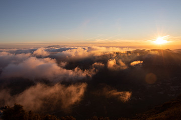 Beautiful mountain peak above the clouds with the sun in the background