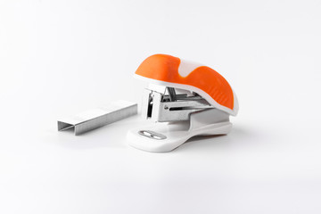 A small orange stapler and staples on a white background. Close-up. Copy space. Space for text