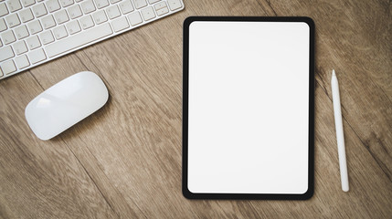 Tablet with black screen over and pen on modern wood office desk table with keyboard computer and , headphones on wooden desk Top view with copy space, flat lay.