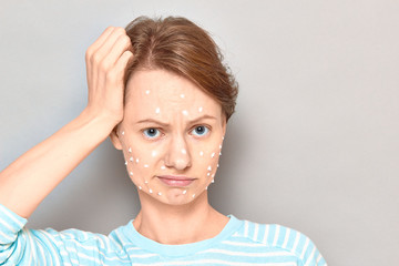 Portrait of disappointed girl with white drops of face cream on skin