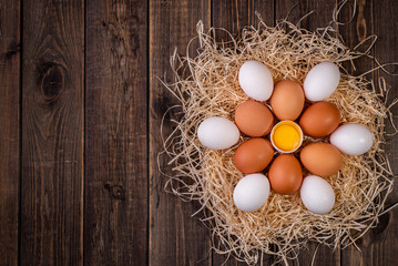 Fresh chicken eggs in a nest of hay on a wooden background. Copy space. Space for text