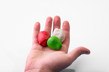 The boy in his hand holds pieces of crumpled plasticine on a white background.