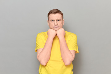 Portrait of focused man propping head with fists and thinking hard