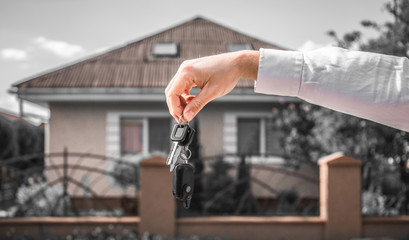 Real Estate Agent Handing Over the House Keys in Front of a Beautiful New Home.