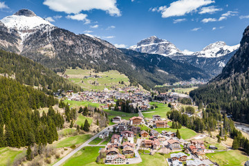 Aerial view of valley with Chalet, green slopes of the mountains of Italy, Trentino, Fontanazzo, huge clouds over a valley, roofs of houses of settlements, green meadows, Dolomites on background,