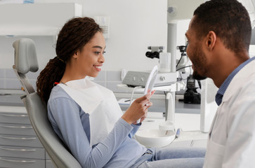 Fototapeta premium Satisfied african lady checking her new smile in mirror