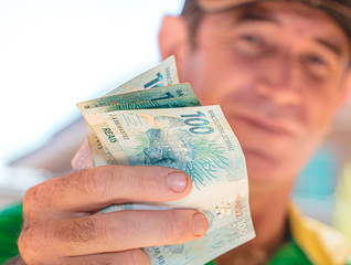 Real. Dinheiro, Brasil, Reais, Money, currency. Man holding in hands a brazilian banknotes.	