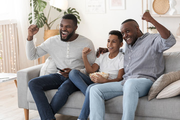 Joyful Black Family, Father, Grandfather And Son Watching Football Match On TV