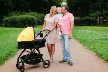 family with a stroller walking in the park on a summer day, family on the weekend