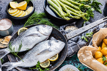 Frischer roher Dorado oder Seebrasse mit Spargel, Gewürzen, Kräutern, Zitrone und Salz auf...