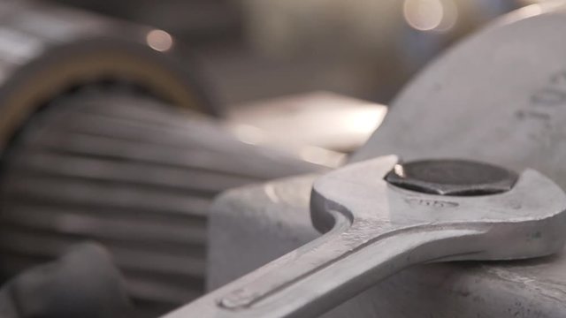 Oper&aacute;rio com chave de boca grande apertando parafuso em m&aacute;quina