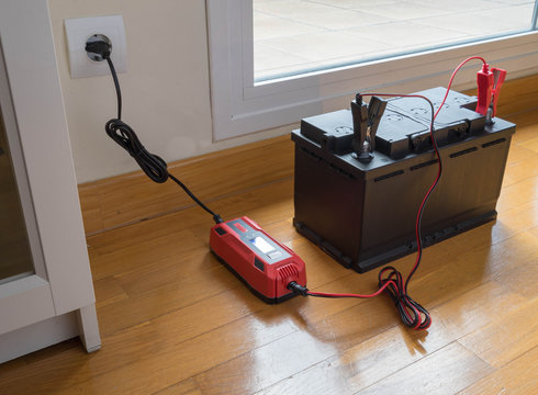 Charging the car battery at home. View of the battery and battery charger