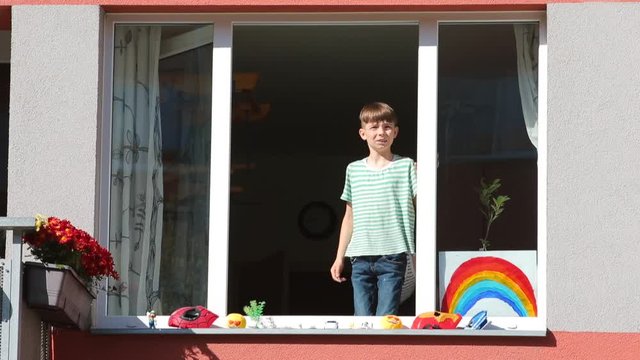 Two boys stand on the windowsill of the window. Communication in self-isolation at home COVID-19. Home education COVID-19.
