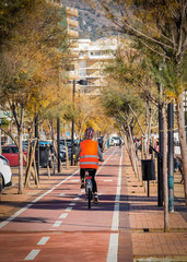 Mujer con chaleco reflectante circulando con su bicicleta por el carril bici de Fuengirola después...