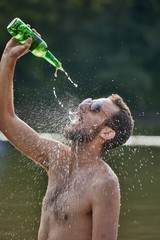Man pouring drink into open mouth from bottle