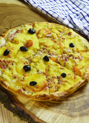 Yellow hearty fresh pizza with cheese on a natural wooden Board. Italian
