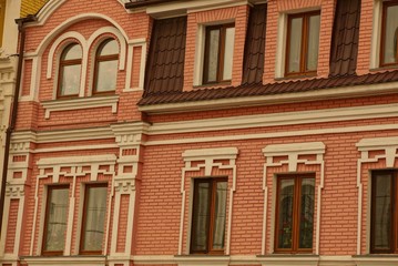 texture of a series of windows on the brown red brick wall of a large multi-storey building on a city street