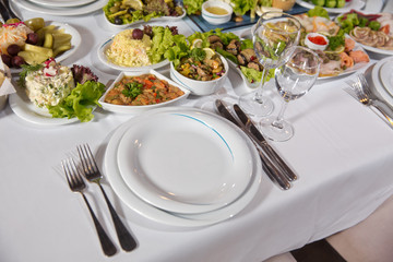 Salads and gums . Set of a dish with spoon, fork and knife on white table.Table setting on white table .