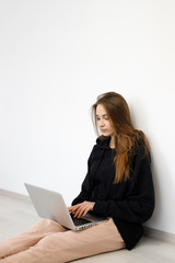 freelancer girl woman in sweater sitting on the floor with laptop computer, concept online education, work from home