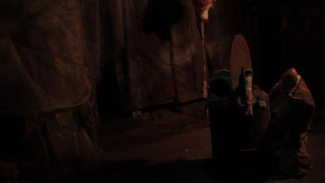 Silhouette of man maniac or killer or horror murderer with chainsaw in hand in dark creepy and spooky room. Criminal robber or rapist concept in thriller atmosphere with  victim girl