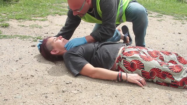 emergency doctor with yellow jacket intervening for a resuscitation of a woman with mouth to mouth respiration