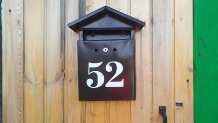 A mailbox in the form of a house hangs on a white wooden door
