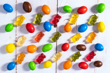 Colorful candy and gummi jelly on white wooden background