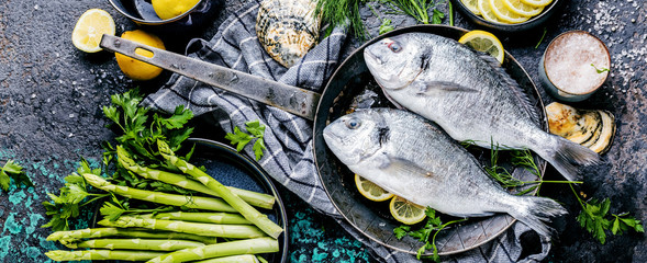 Frischer roher Dorado oder Seebrasse mit Spargel, Gewürzen, Kräutern, Zitrone und Salz auf...