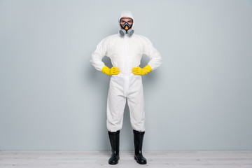 Full length photo of professional guy disinfectant watch public places clean disinfection wear white hazmat protective suit goggles mask gloves gumboots isolated grey color background
