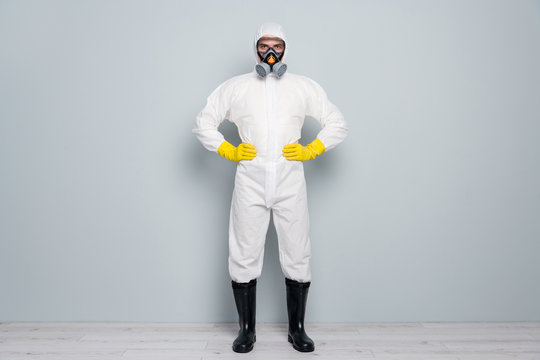 Full length photo of professional guy disinfectant watch public places clean disinfection wear white hazmat protective suit goggles mask gloves gumboots isolated grey color background