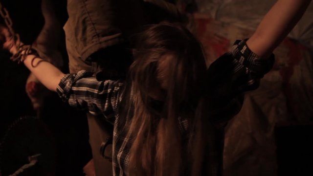 Silhouette of man maniac or killer or horror murderer with chainsaw in hand in dark creepy and spooky room. Criminal robber or rapist concept in thriller atmosphere with  victim girl