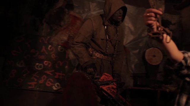 Silhouette of man maniac or killer or horror murderer with chainsaw in hand in dark creepy and spooky room. Criminal robber or rapist concept in thriller atmosphere with  victim girl