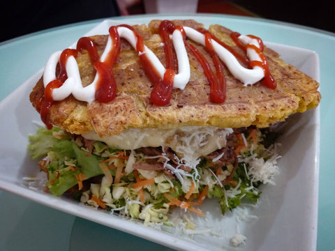 Traditional venezuelan patacon fried plantain sandwich filled with shredded beef and vegetables
