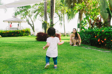 Asian little girl running and walking on grass field.