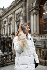 Fototapeta premium A blonde in a white down jacket is walking in the old city