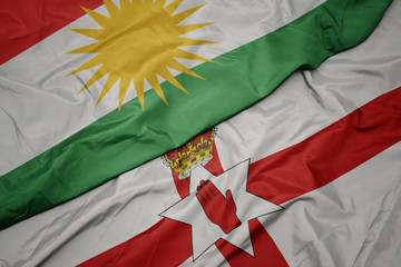 Obraz premium waving colorful flag of northern ireland and national flag of kurdistan.