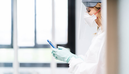 A female doctor using mobile phone wearing safety clothes