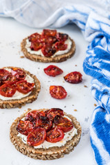 Round slices of wholemeal bread with grilled tomatoes on cream cheese