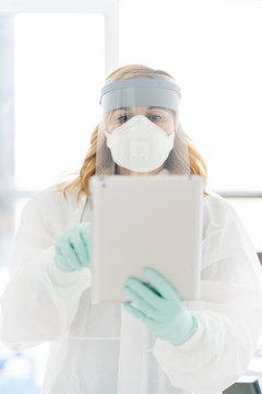 A Female Doctor Using An Ipad With Safety Equipment.