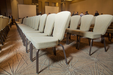 White chairs in the conference room. empty seat in conference meeting hall . White Chairs in the Conference Room just before a business meeting takes place.