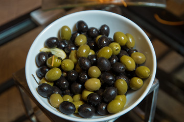 Top view with space for text . Green and black olives in a white ceramic bowl .
