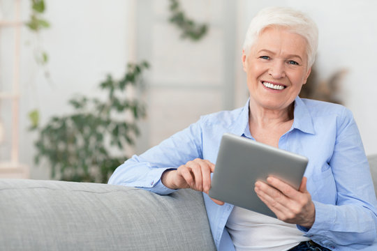 Smiling Beautiful Senior Woman Using Digital Tablet At Home, Empty Space, Close Up