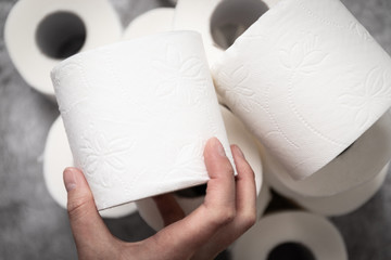 A female hand takes a roll of toilet paper for its intended use.