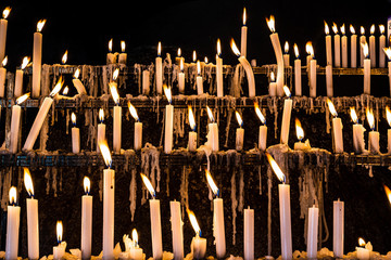 hundreds of candles at a wake, lit by religious looking for graces and promises - 343583370