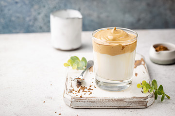 Dalgona Coffee, a cool fluffy whipped coffee in a glass. Latte espresso with coffee foam in tall glass. Trendy drink