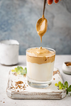 Dalgona Coffee, a cool fluffy whipped coffee in a glass. Latte espresso with coffee foam in tall glass. Trendy drink