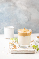 Dalgona Coffee, a cool fluffy whipped coffee in a glass. Latte espresso with coffee foam in tall glass. Trendy drink