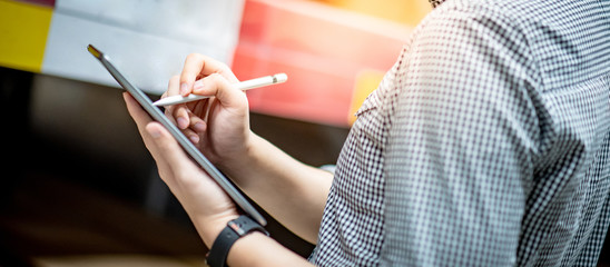 Close up of male hand using digital pen writing on digital tablet screen. Modern technology with electronic gadget concept 