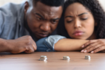 Coronacrisis Concept. Depressed Black Couple Looking At Stacks Of Golden Coins